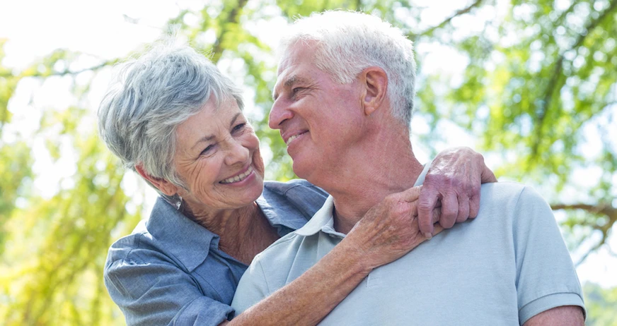Happy old couple smiling in a park on a sunny day